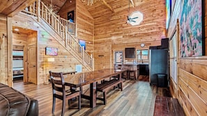 A wooden interior with a dining area, kitchen, and staircase.
