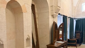 Una habitación con techos abovedados, un aparador de madera, un espejo, una mesa y una alfombra estampada.