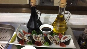 A plate of sushi rolls with soy sauce and wasabi, and two bottles of oil. - Jozani biosphere village  (Jozani)