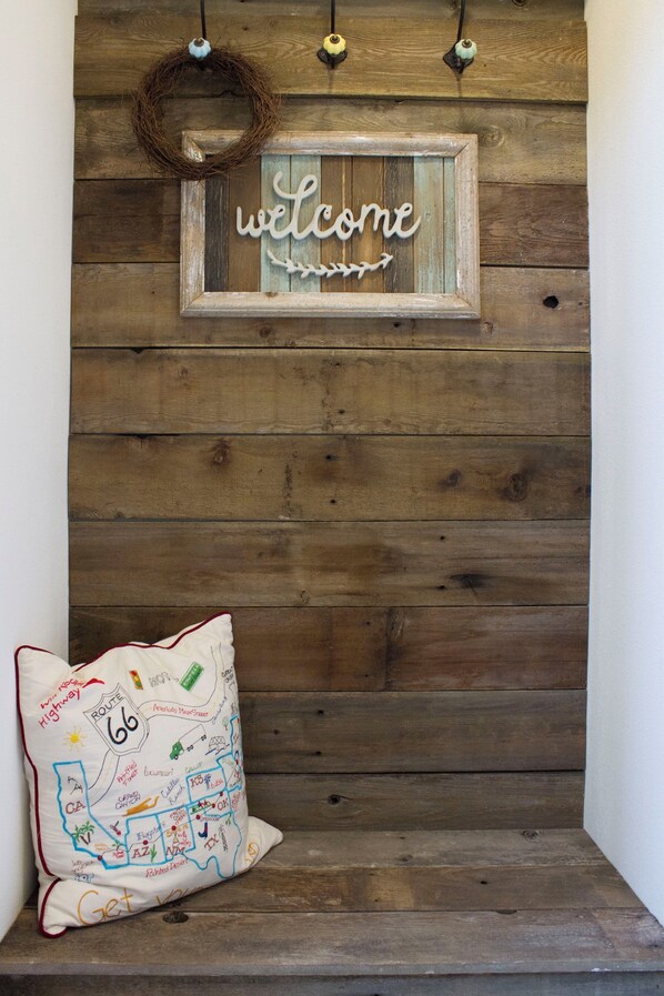 Pared de madera con un letrero que dice 'welcome' y un cojín de la Ruta 66.