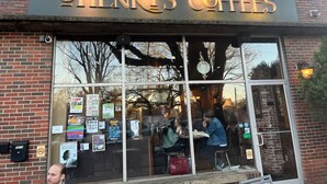 A storefront with a sign reading 'Henry's Coffees' and a glass door reflecting the interior.