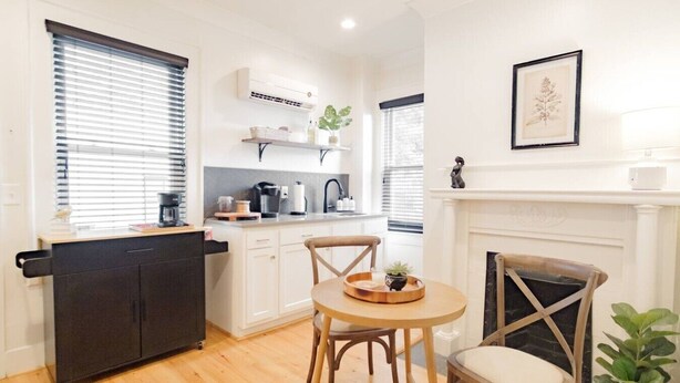 A compact kitchen with a dining area, a fireplace, and a small plant.