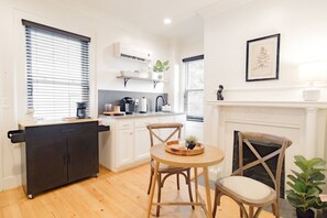 A compact kitchen with a dining area, a fireplace, and a small plant. - Moroccan Dreams Suite, Walkable to Highland Park! (Birmingham)