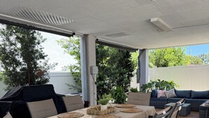 Un patio al aire libre con una mesa dispuesta para seis personas, rodeada de sillas, una parrilla y un sofá.