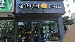 Placa de hotel com o nome '途径中国 HOTEL' e um logotipo.