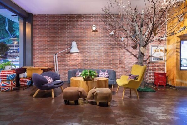 A cozy lounge area with a brick wall, a round wooden table, and modern seating including a sofa and chairs. - Tuke China Hotel (Taizhou Luqiao Shili Branch) (Taizhou)