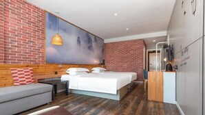 Quarto de hotel moderno com parede de tijolos, uma cama grande, um sofá e uma escrivaninha.