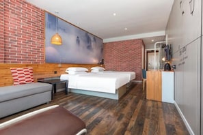 Een moderne hotelkamer met een bakstenen muur, een groot bed, een bank en een bureau.