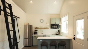 A modern kitchen with a refrigerator, microwave, and bar stools. - NEW Farm Stay Cabin close to Livingston, Yellowstone, Bozeman, fishing, hiking (Livingston)