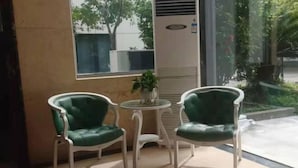 A seating area with two green upholstered chairs and a small round table, positioned near a window with a view of greenery outside. - Junting Hotel, Taohua Island (Zhoushan)