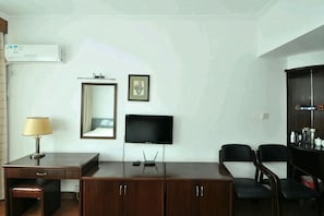 A room with a desk, chairs, a TV, a mirror, and a cabinet. - Junting Hotel, Taohua Island (Zhoushan)