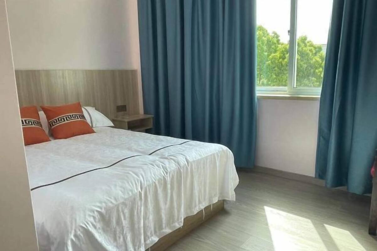 A hotel room with a bed, a nightstand, and a window with curtains.