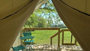 Een tent met een houten terras, een tafel en stoelen.