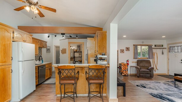 Eine geräumige Küche mit Holzausbau, einem weißen Kühlschrank und einer Bar mit zwei Hockern.