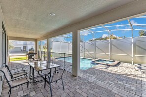 A covered patio area with a pool, outdoor seating, and a grill. - Exclusive Champions Gate Retreat w/ Private Pool (Davenport)