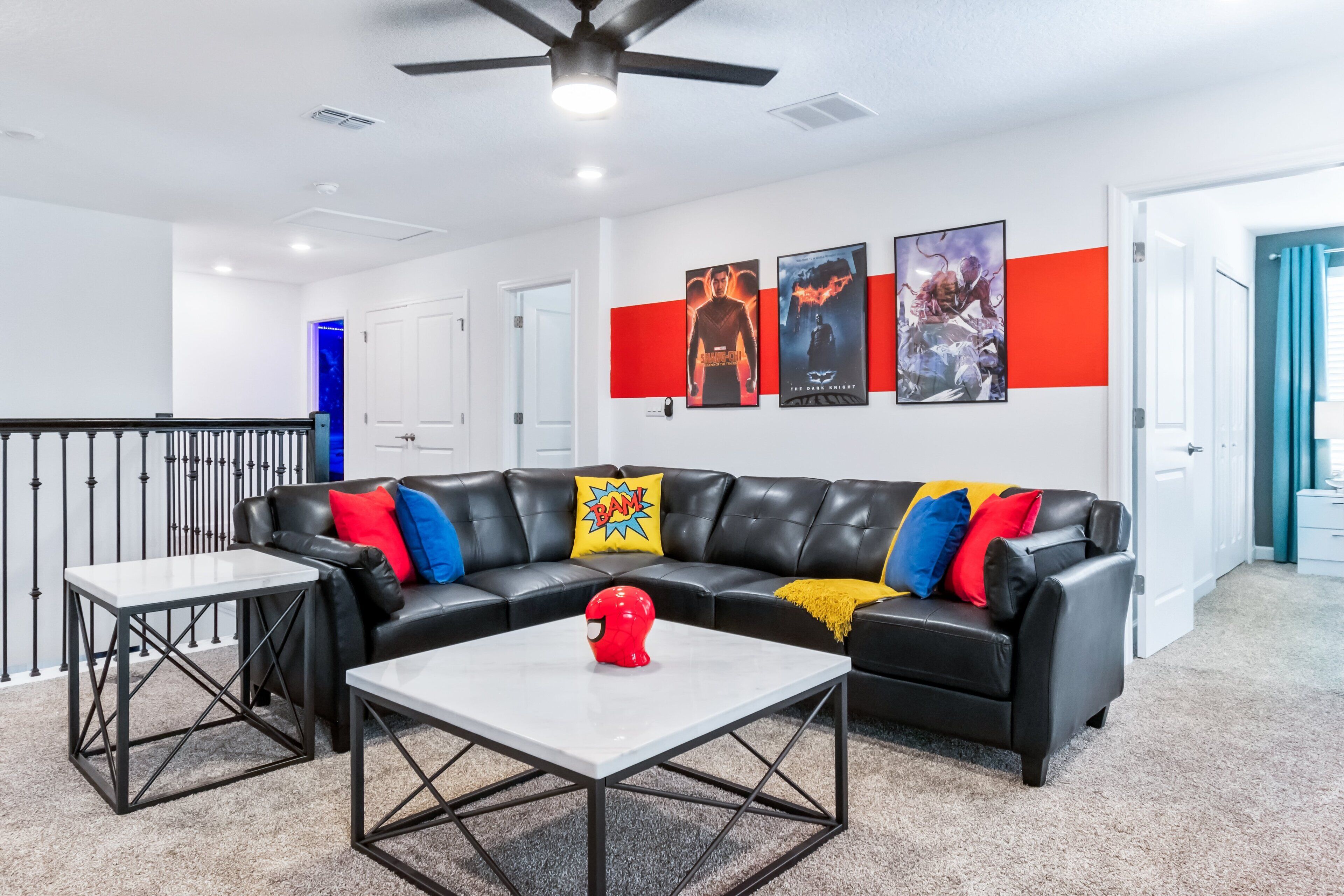 A modern living room with a black leather sectional sofa, two white coffee tables, and a red helmet decoration.