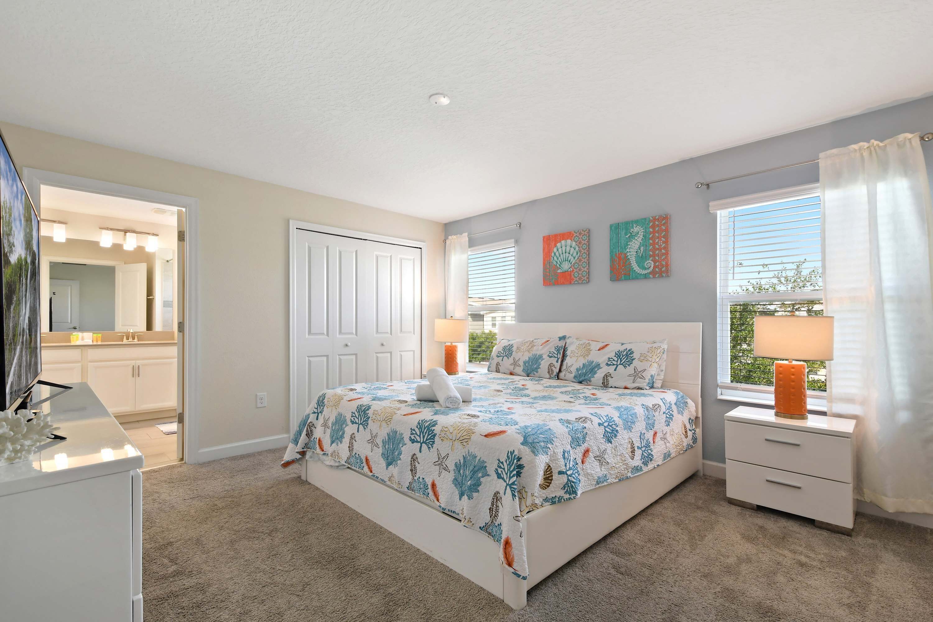 Un dormitorio con cama, mesitas de noche, cómoda, espejo y ventana con cortinas.