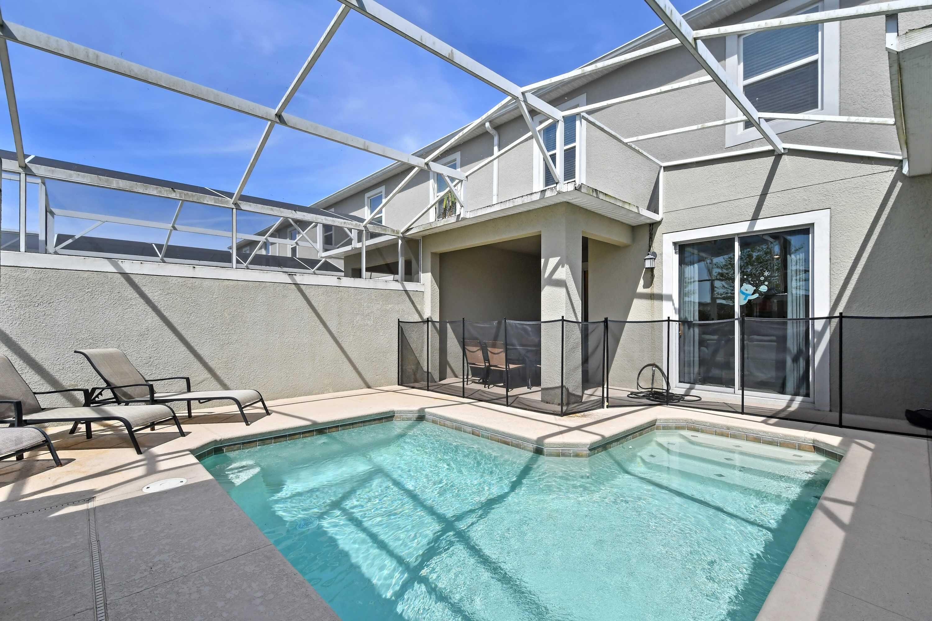A rooftop pool area with a clear blue pool, lounge chairs, and a covered seating area.