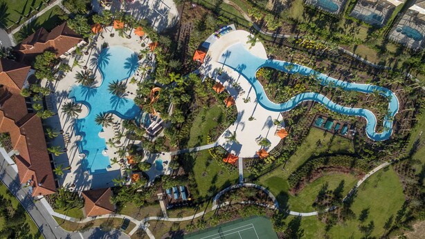 Eine Vogelperspektive zeigt ein Resort mit mehreren Schwimmbecken, einer Wasserrutsche und üppiger Bepflanzung.