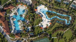 Eine Vogelperspektive zeigt ein Resort mit mehreren Schwimmbecken, einer Wasserrutsche und üppiger Bepflanzung.