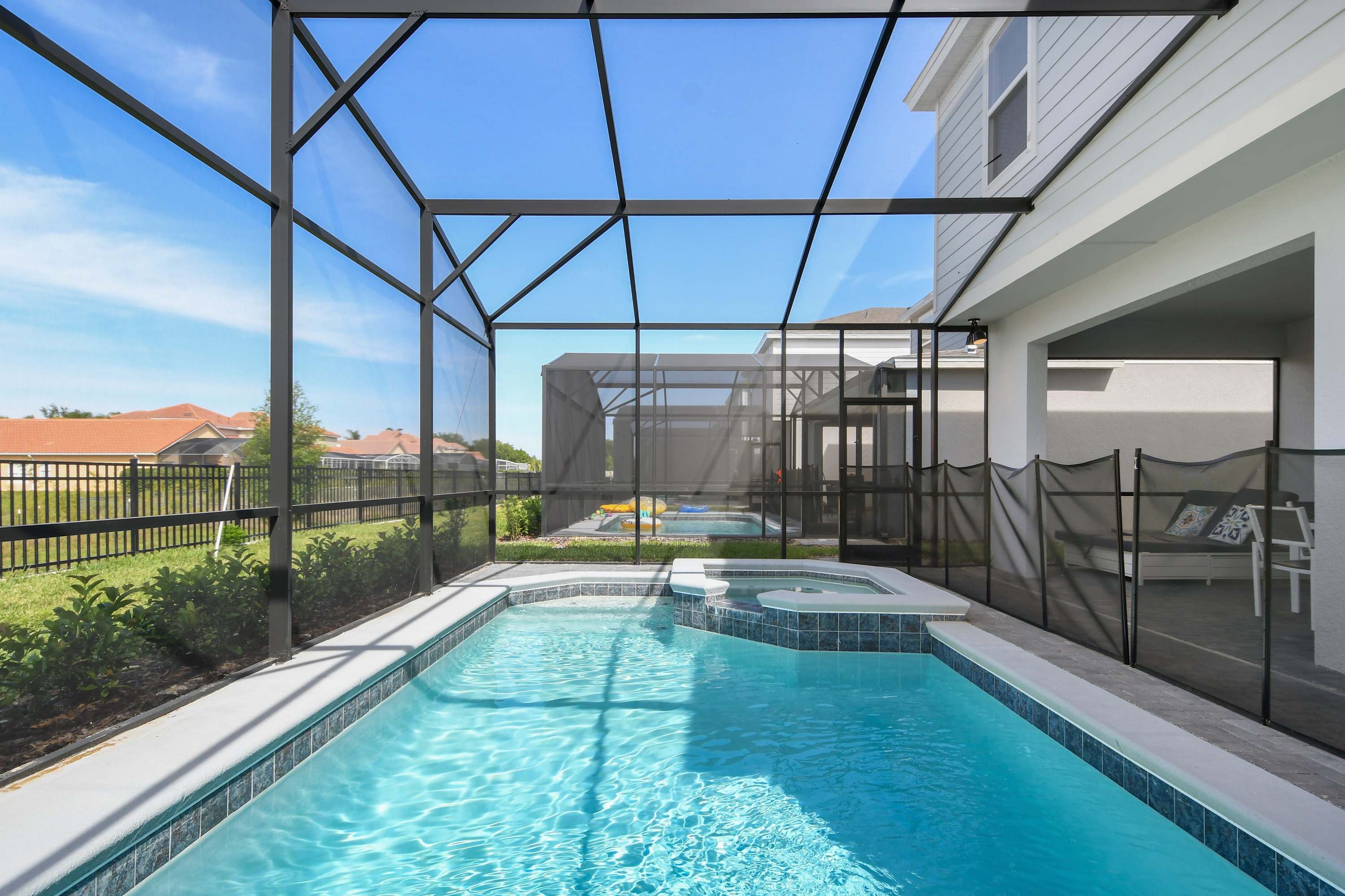 Une piscine dotée d’une enceinte en verre, un jacuzzi et un espace salon couvert.