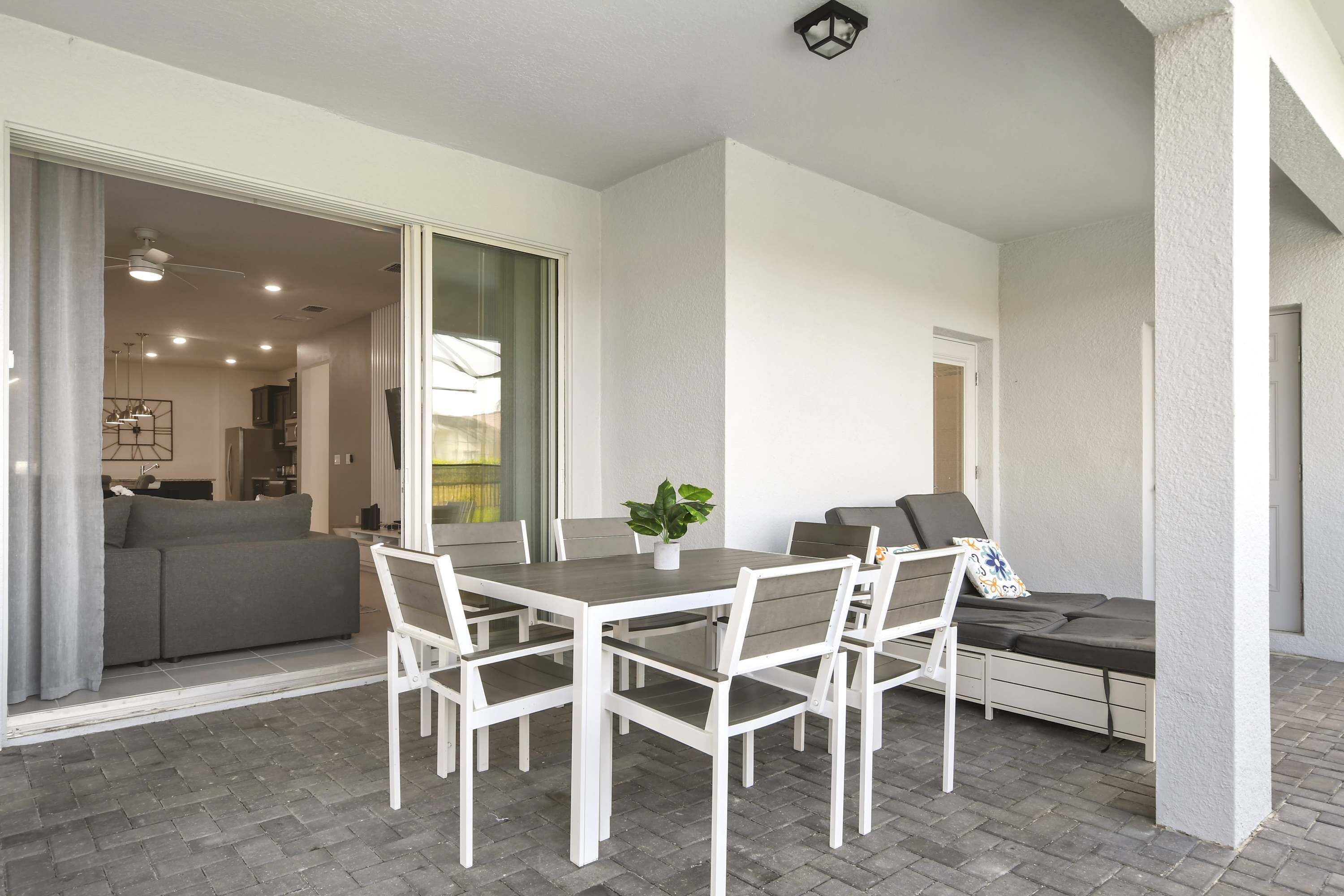 A patio with a dining table, chairs, a potted plant, and a sofa.