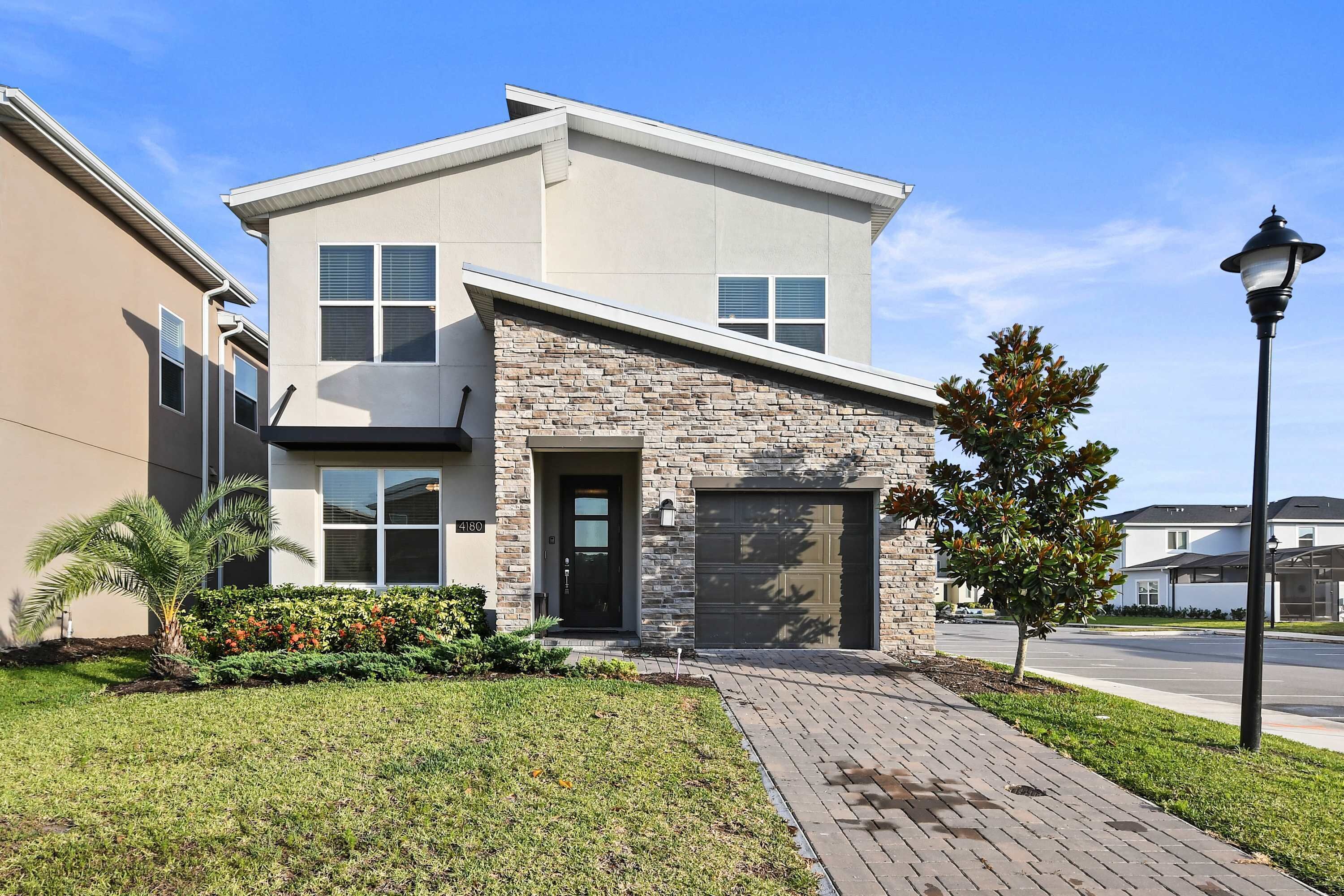 A modern two-story house with a stone facade, a garage, and a well-maintained lawn.