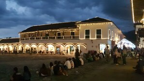 A historic building with arched walkways and a flat-roofed structure, surrounded by a crowd of people. - Casa de la Villa (Villa de Leyva)