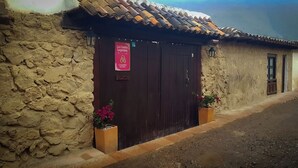 A hostel with a rustic stone facade, a dark wooden door, and a sign indicating it is a 'Coliving Hostel'. - Casa de la Villa (Villa de Leyva)