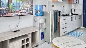 Eine moderne Küche mit weißen Schränken, einem Edelstahl-Kühlschrank, einem Wasserspender und einem Essbereich mit einem Marmortisch.