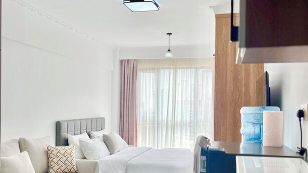 Ein Hotelzimmer mit einer Couch, einem Bett, einem kleinen runden Tisch und einer Küchenzeile.