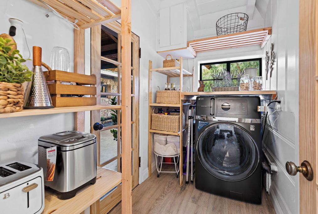 A compact kitchen with a washing machine, a toaster, and a grater on the counter.