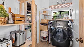 A compact kitchen with a washing machine, a toaster, and a grater on the counter.