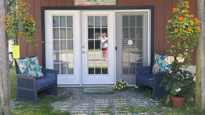 A wooden building with a covered porch, two benches, and a potted plant with yellow flowers.