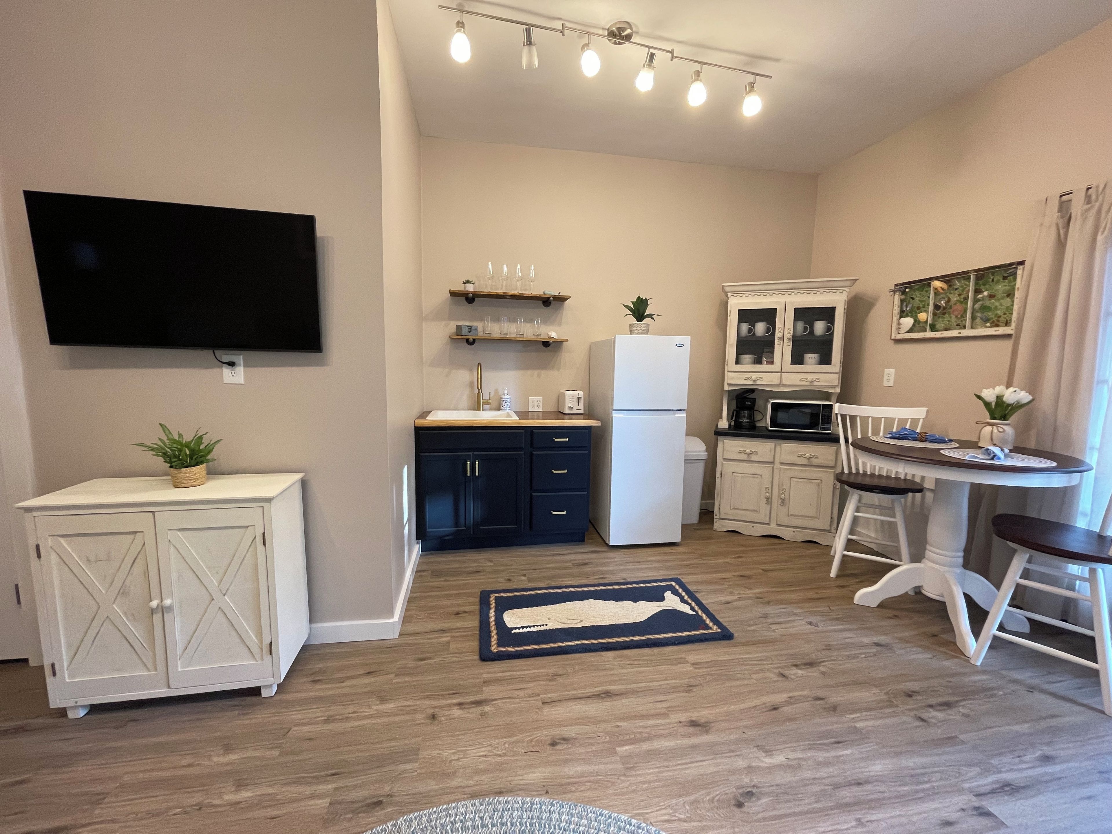 A compact kitchen with a refrigerator, microwave, and a dining area with a table and chairs.