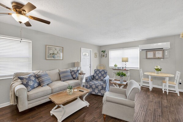 A living room with a sofa, armchair, coffee table, and a dining area with a table and chairs.