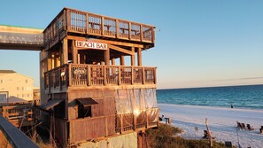 A wooden beach bar structure with a sign reading "BEACH BAR" and "OREN" on the side.