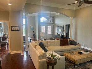 Relax in this stylish living room with a high ceiling, large window, and comfortable seating area.
