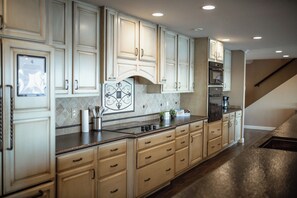 A kitchen with light-colored cabinets, a tiled backsplash, and a stainless steel range hood.