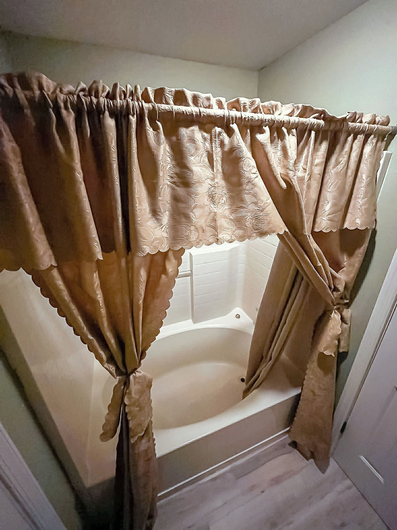 A bathroom with a bathtub, a shower, and a curtain.