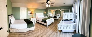 A bedroom with a bed, a crib, a ceiling fan, and a mirror.