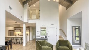 A spacious interior with a high ceiling, a kitchen area, and a seating area with two green chairs. - 201 Verbier Building 4 (Mont-Tremblant)