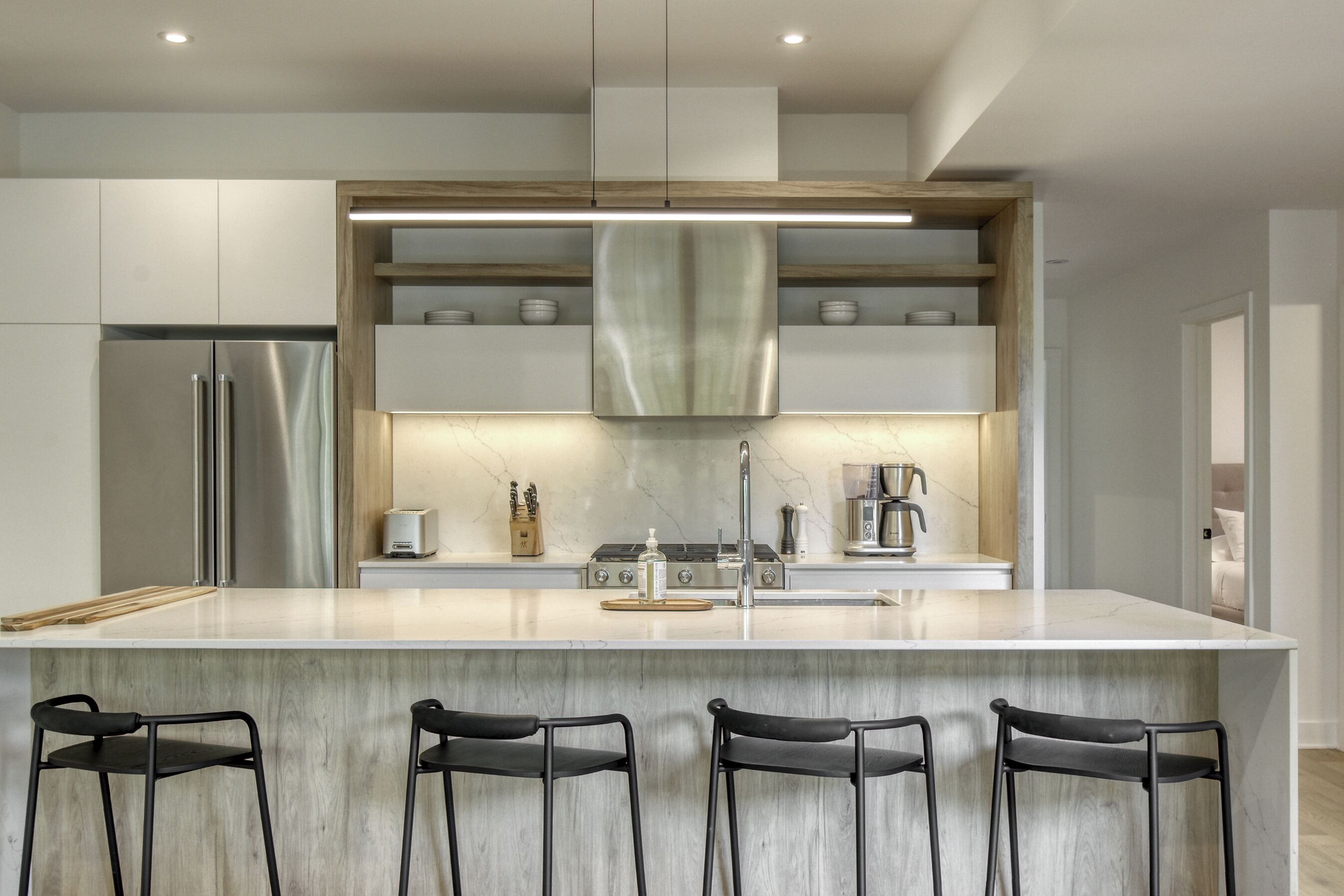 A modern kitchen with a large island, stainless steel appliances, and bar stools.