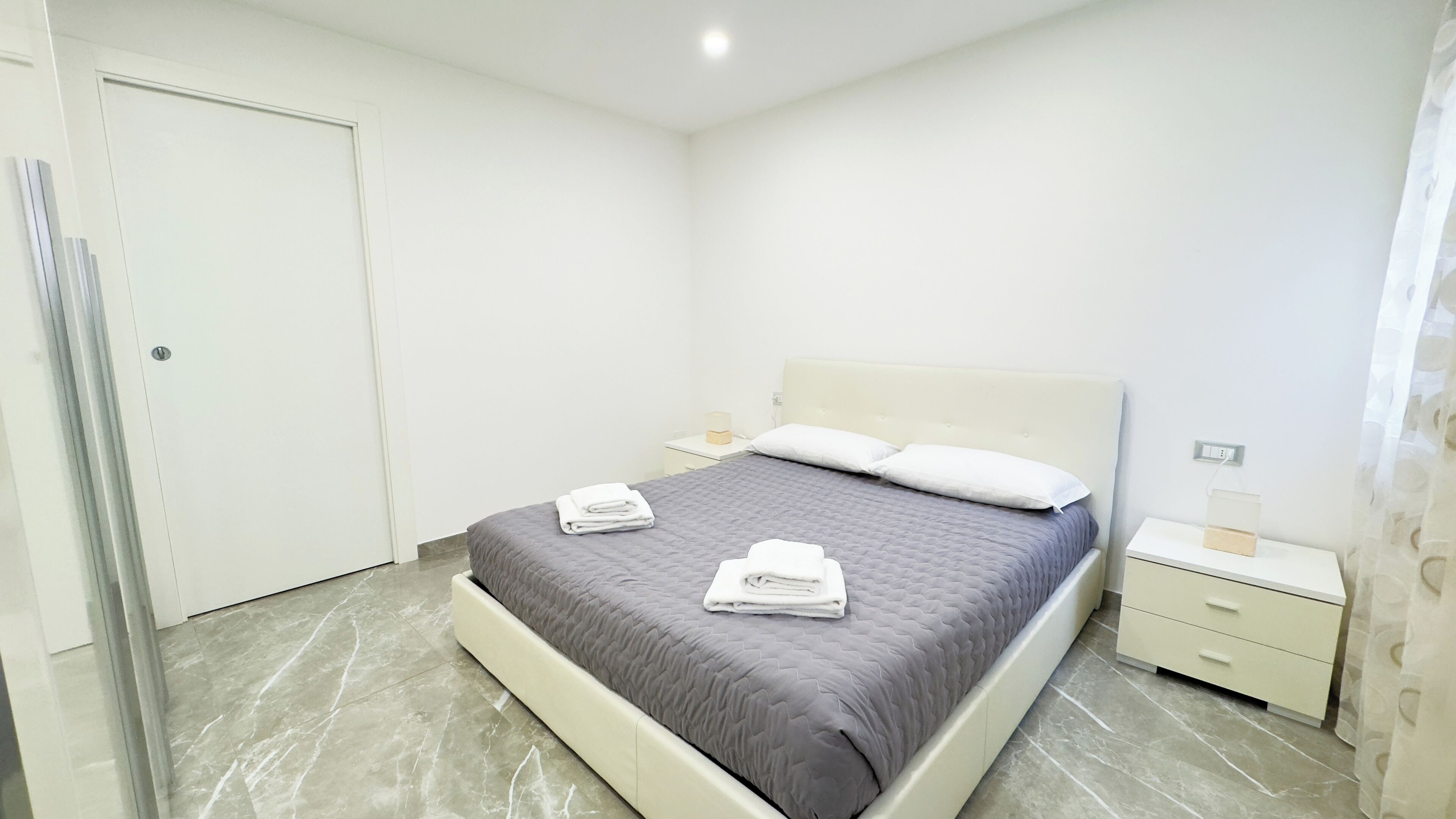 Un dormitorio moderno con cama, mesita de noche y una puerta.