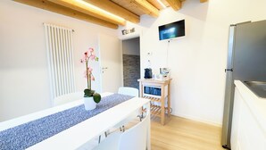 A modern kitchen with a built-in refrigerator, a microwave, and a coffee machine on a small wooden table. - Maison la Digue by Ca-Sa Check (Chioggia)