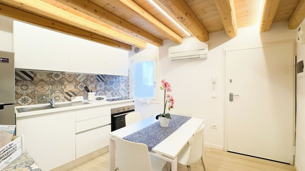 A modern kitchen with white cabinetry, a tiled backsplash, and a wooden ceiling. - Maison la Digue by Ca-Sa Check (Chioggia)
