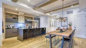 A modern kitchen with a central island, bar stools, and a dining table with chairs. - 102 Verbier Building 7 - Alpinhaus (Mont-Tremblant)