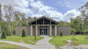 A modern building with a symmetrical facade, a central entrance, and a paved pathway leading to it. - 102 Verbier Building 7 - Alpinhaus (Mont-Tremblant)