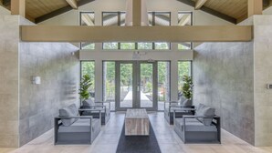 A modern lobby with a high ceiling, large windows, and a central seating area with sofas and a coffee table. - 102 Verbier Building 7 - Alpinhaus (Mont-Tremblant)