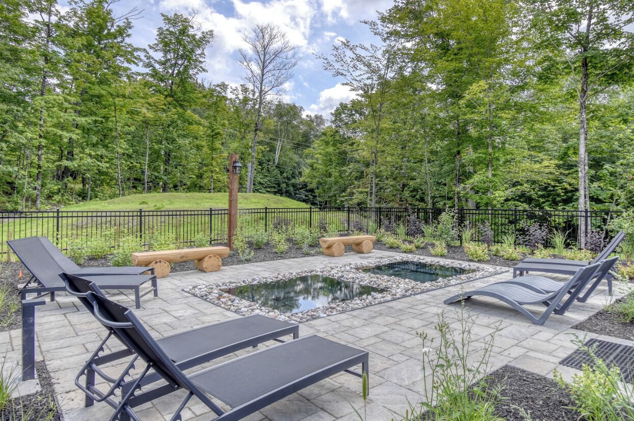 An outdoor patio with lounge chairs, a small pond, and a wooden bench.